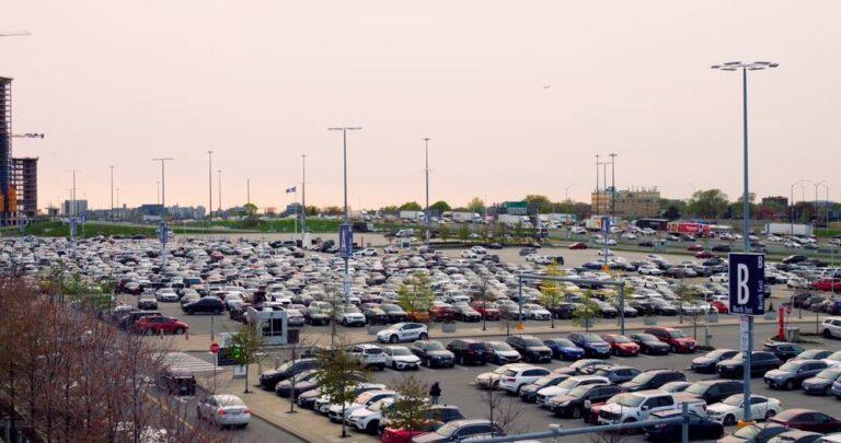 Large crowded parking lot filled with vehicles and surrounding traffic congestion during Canada Day long weekend travel.