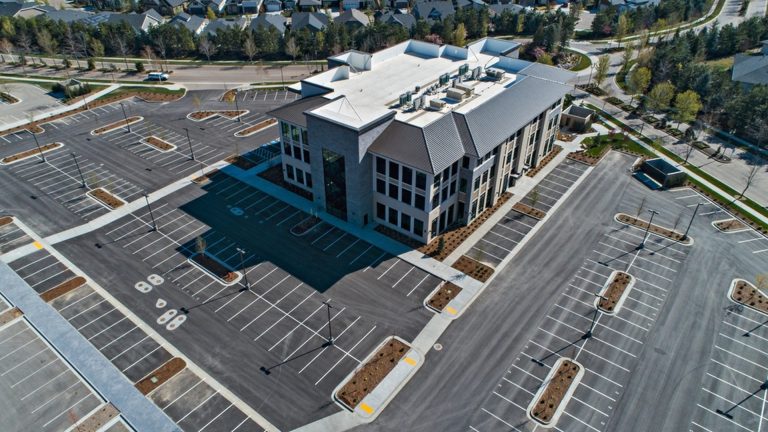 Aerial view of a commercial parking lot in Mississauga surrounding a modern office building, featuring newly paved asphalt, marked parking spaces, and organized traffic lanes.
